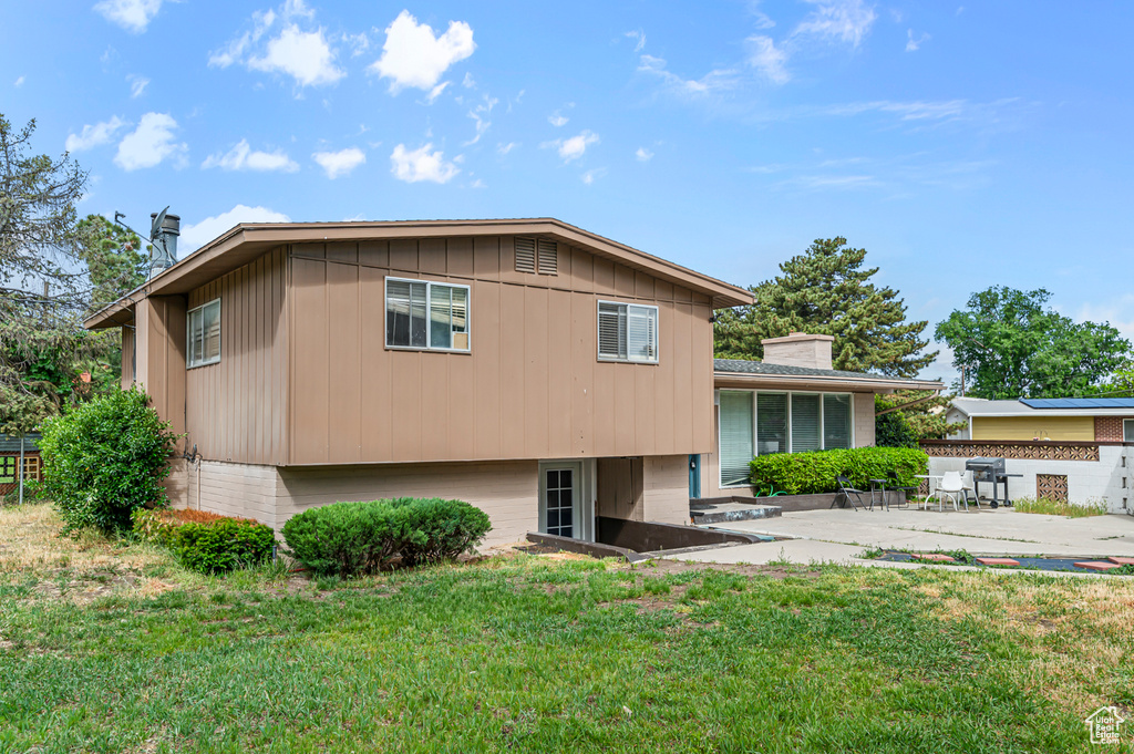 Back of property featuring a patio area, a chimney, and board and batten siding