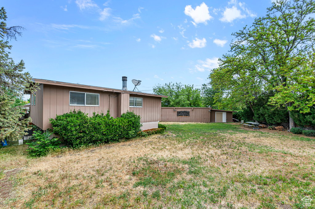 Rear view of property with board and batten siding and a lawn