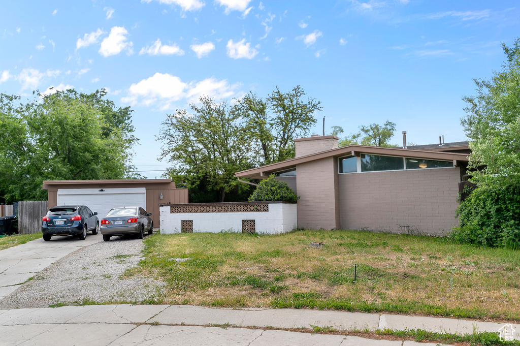 View of side of property with concrete driveway, a chimney, and a garage