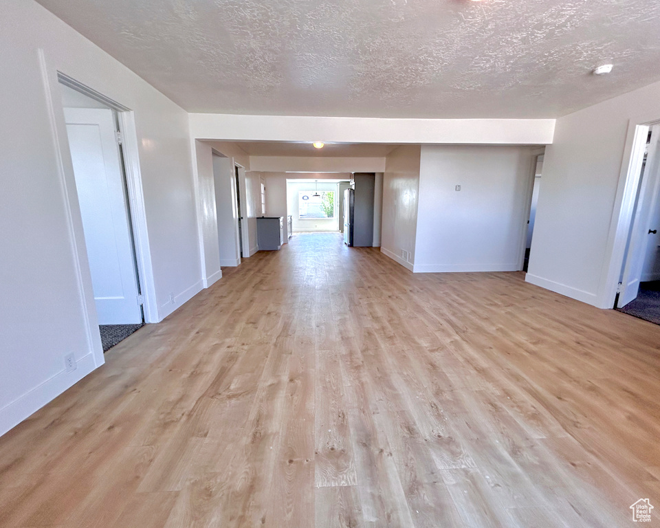 Spare room with a textured ceiling, light wood finished floors, and baseboards