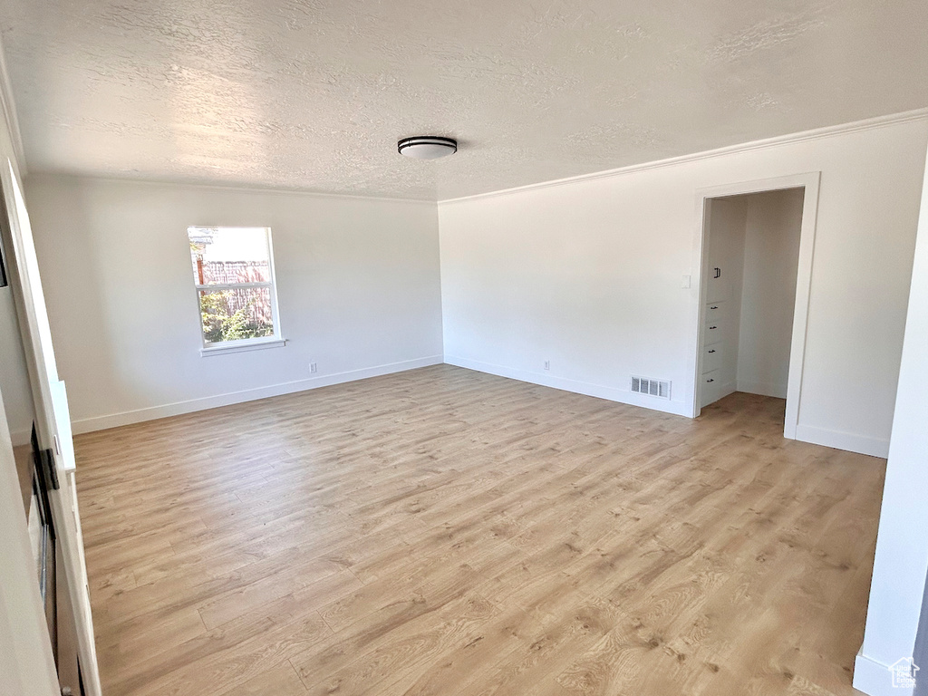 Unfurnished room with a textured ceiling, light wood-style flooring, and baseboards