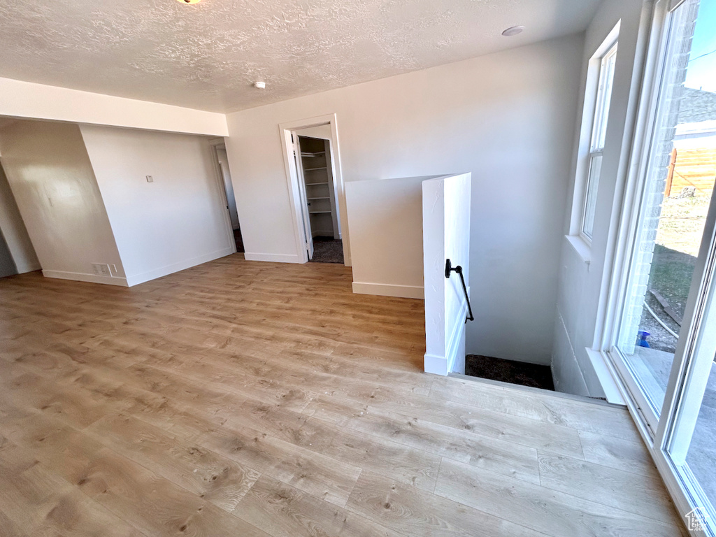 Spare room featuring light wood-type flooring, baseboards, and a textured ceiling