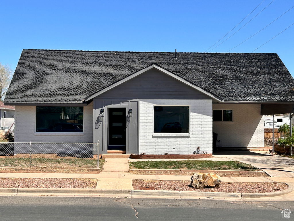 Bungalow-style home featuring brick siding, an attached carport, and driveway