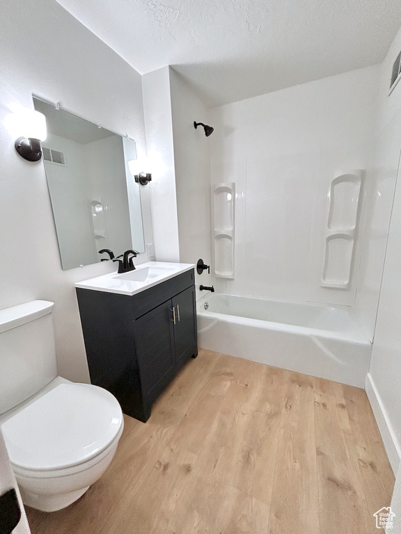 Full bathroom with wood finished floors, shower / bathtub combination, toilet, and vanity