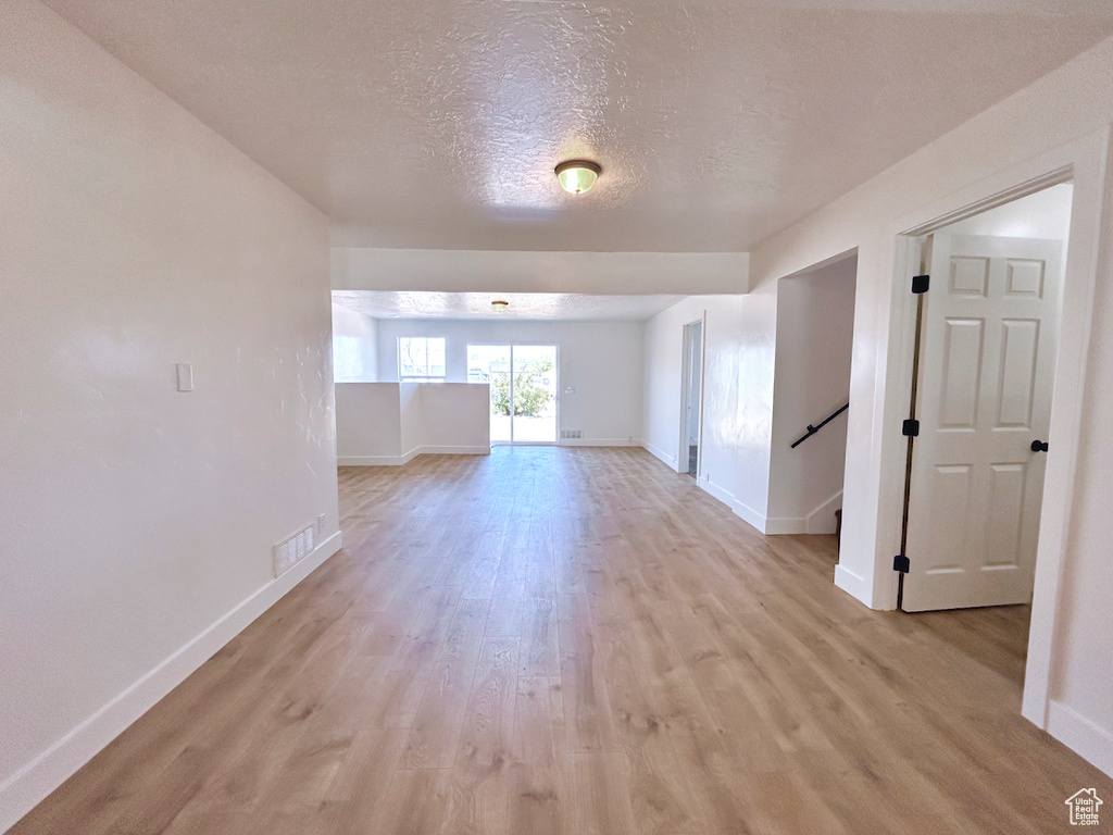 Empty room with baseboards, light wood finished floors, and a textured ceiling