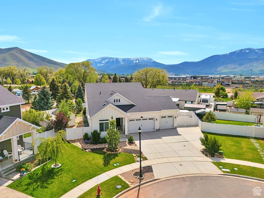 View of front facade with board and batten siding, a garage, a mountain view, and concrete driveway