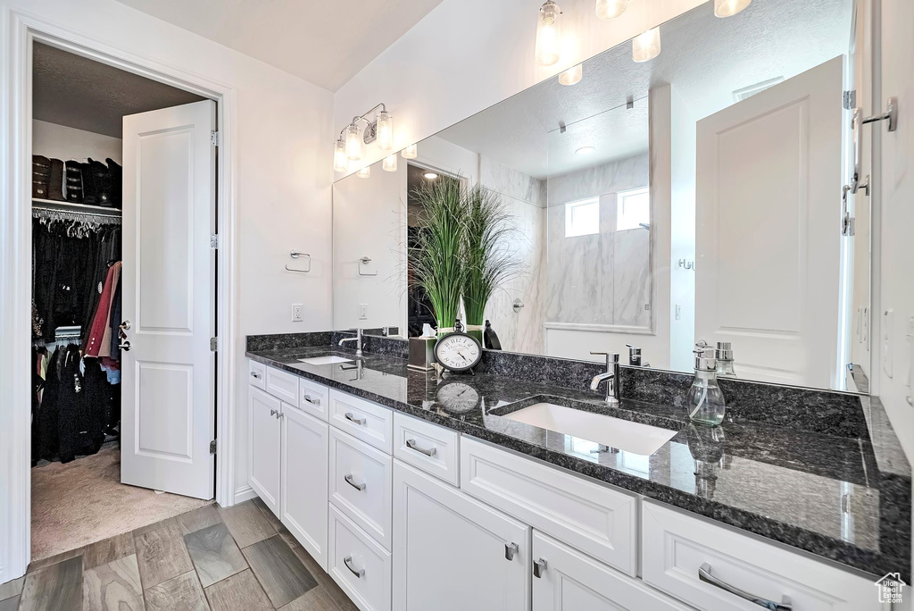 Full bathroom with double vanity and a walk in closet