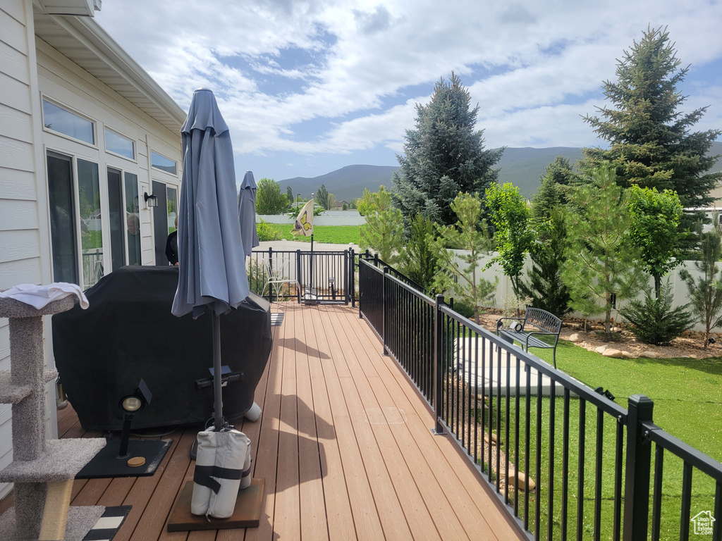 Deck featuring a mountain view, a lawn, and a grill