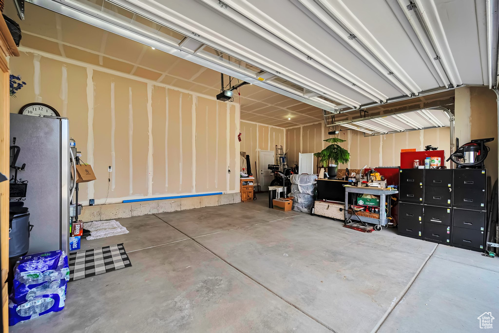 Garage featuring a garage door opener and freestanding refrigerator