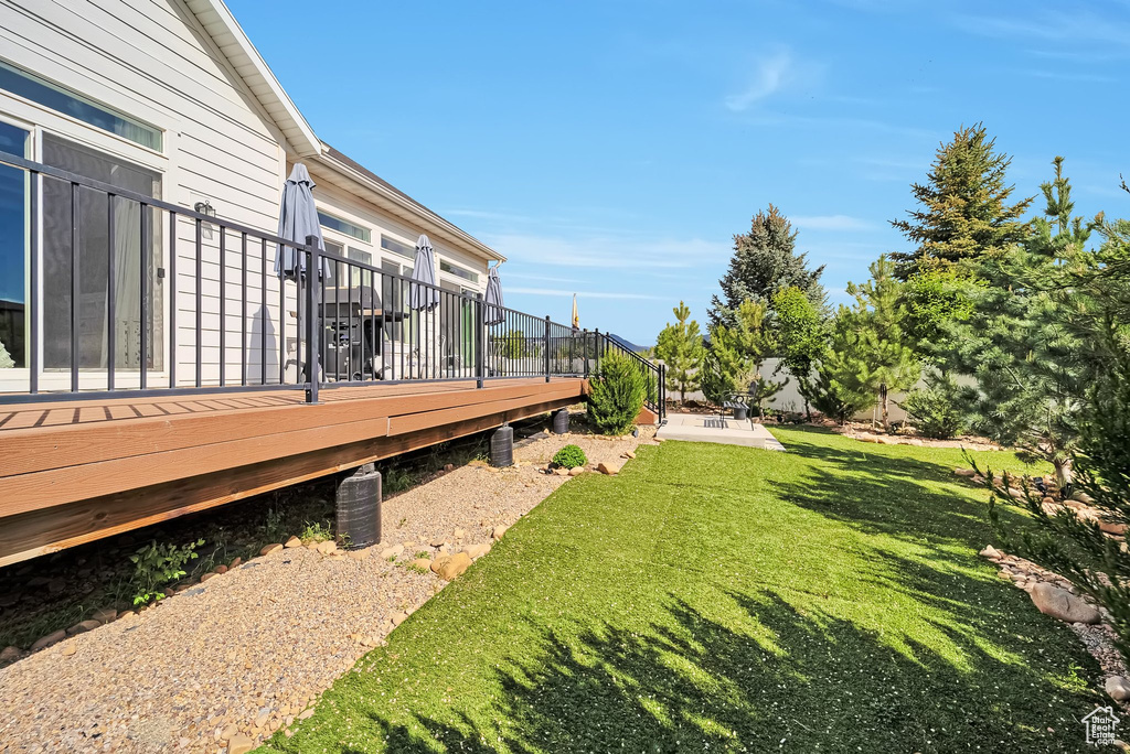 View of grassy yard featuring a wooden deck