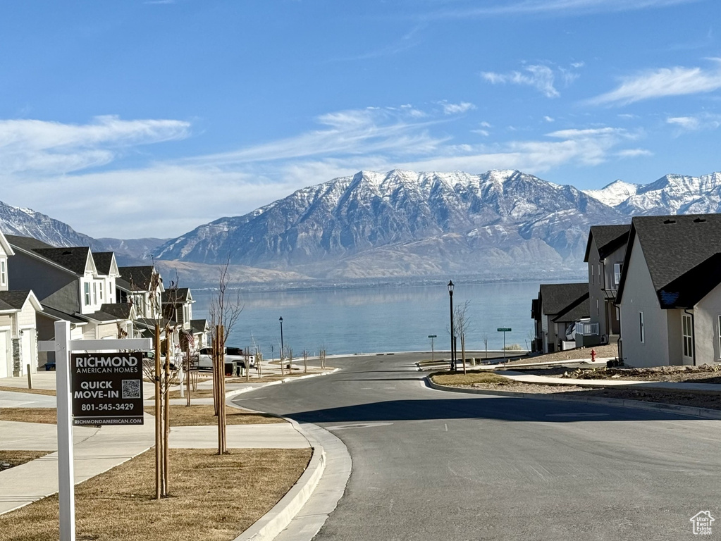 View of asphalt street with a water and mountain view and curbs