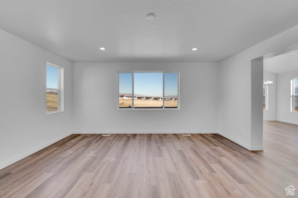 Unfurnished room with healthy amount of natural light, light wood-style flooring, a chandelier, and recessed lighting