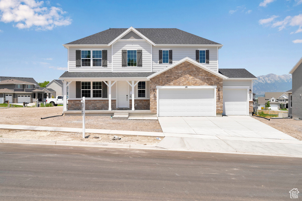 Craftsman-style home with covered porch, driveway, stone siding, and a garage