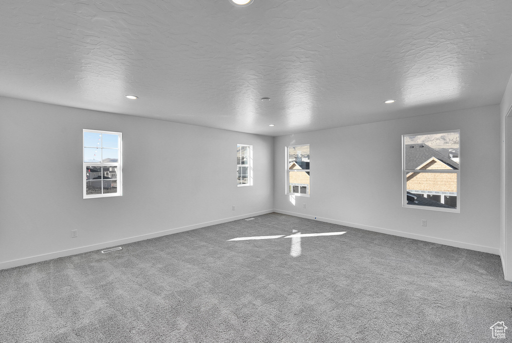Carpeted empty room featuring a textured ceiling, recessed lighting, and baseboards
