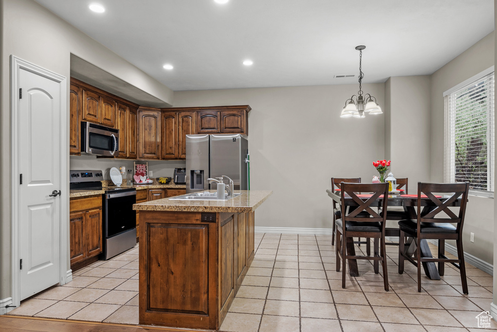 Kitchen featuring appliances with stainless steel finishes, a sink, baseboards, an island with sink, and recessed lighting