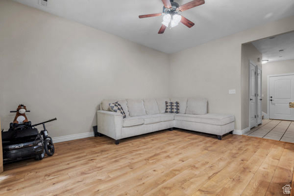 Living room with wood finished floors, ceiling fan, and baseboards