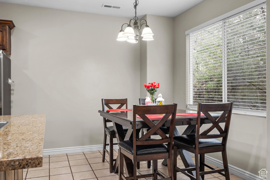 Dining space featuring a chandelier, light tile patterned floors, and baseboards