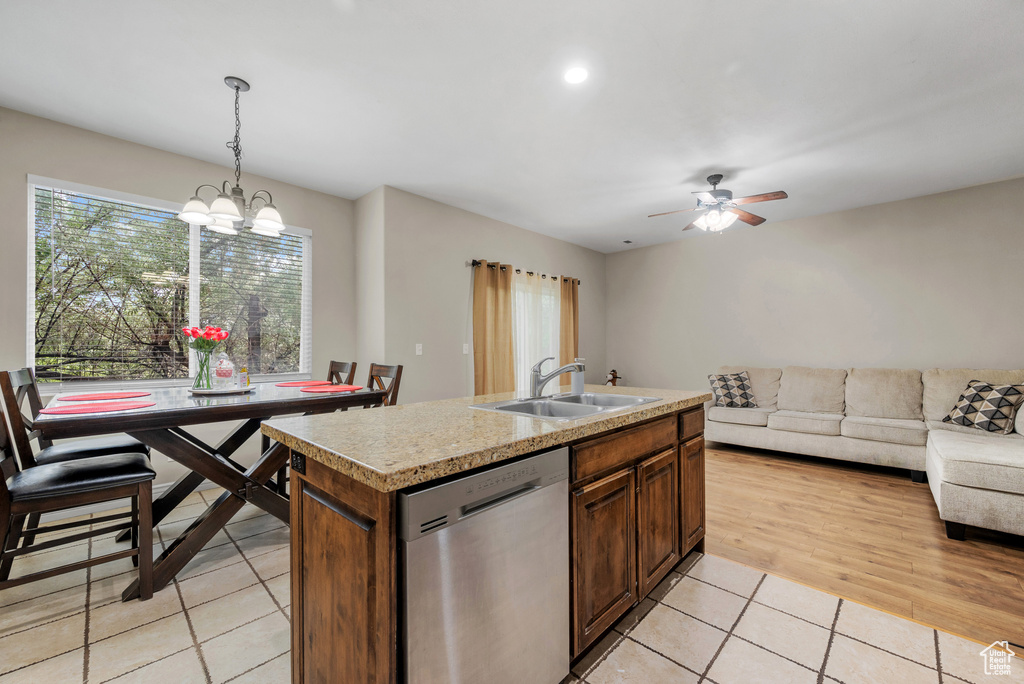Kitchen featuring stainless steel dishwasher, a sink, open floor plan, light countertops, and light tile patterned floors