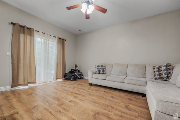Living room featuring light wood-style flooring, ceiling fan, and baseboards