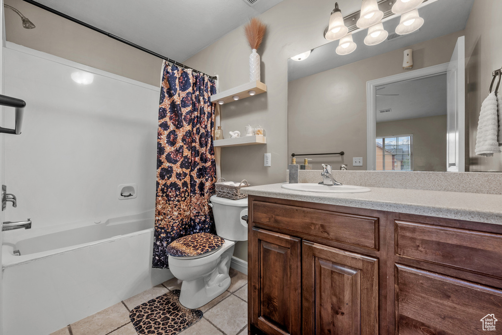 Full bathroom with tile patterned floors, toilet, vanity, and shower / tub combo with curtain