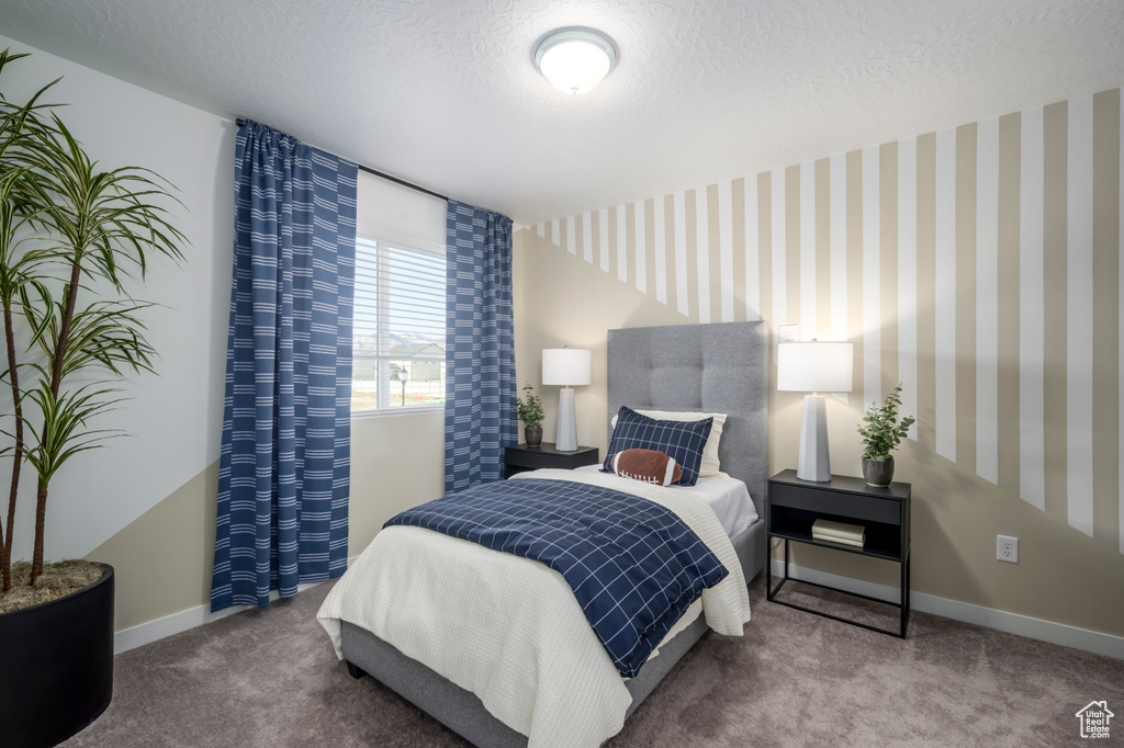 Carpeted bedroom featuring baseboards and a textured ceiling