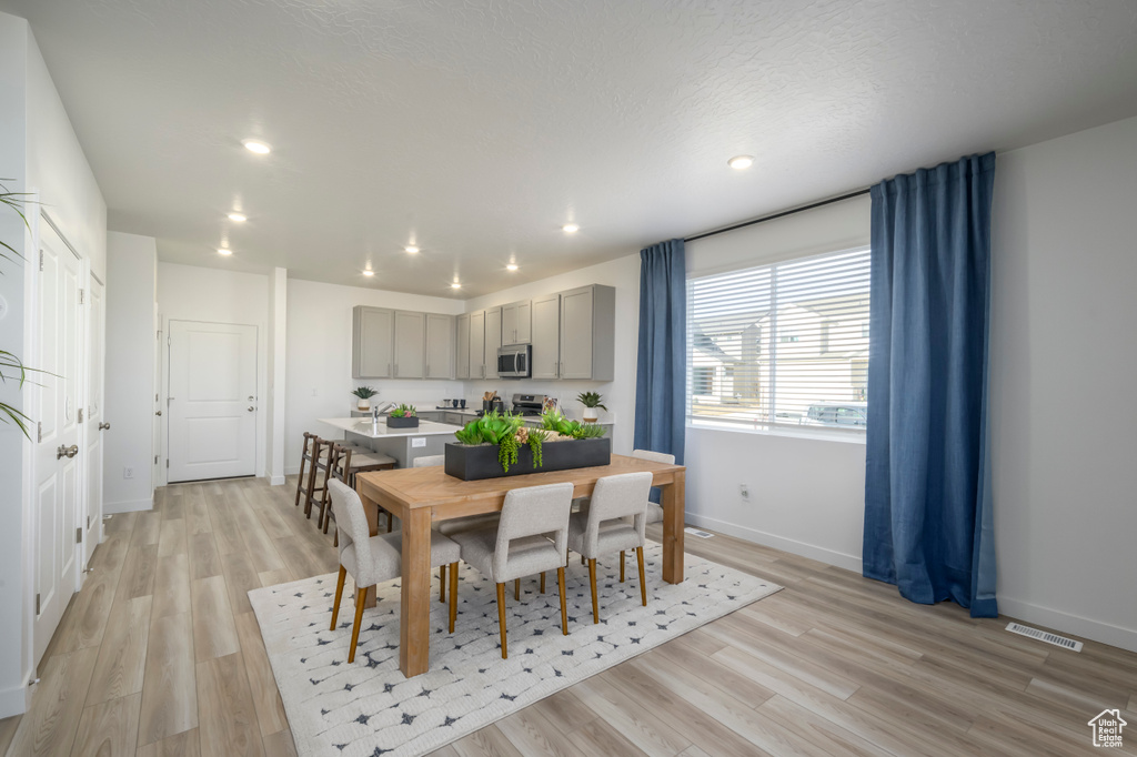 Dining room featuring baseboards, light wood-style floors, and recessed lighting
