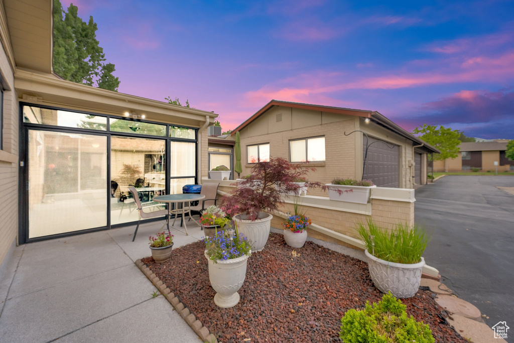 View of front facade featuring asphalt driveway, an attached garage, an outdoor structure, and a patio