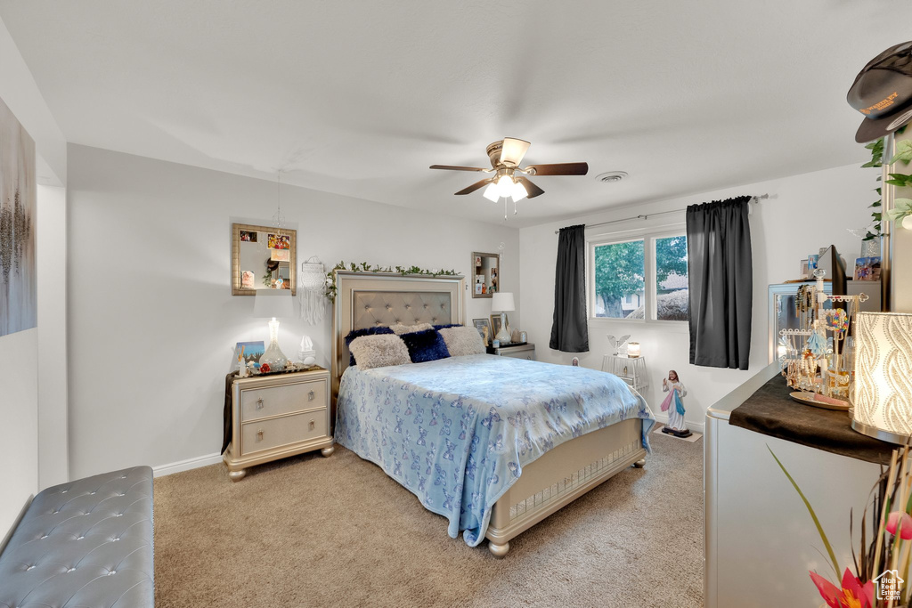 Bedroom featuring light carpet, a ceiling fan, and baseboards