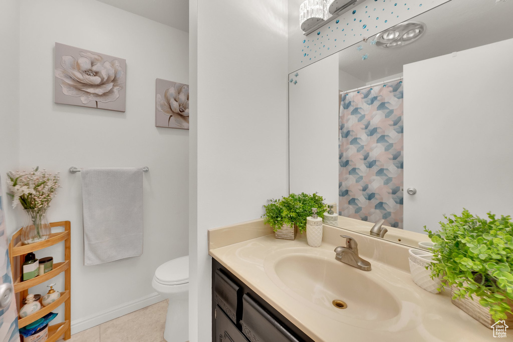 Bathroom featuring toilet, vanity, tile patterned floors, and curtained shower