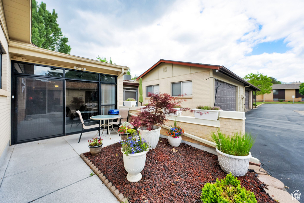 View of patio / terrace featuring a garage, a sunroom, and driveway