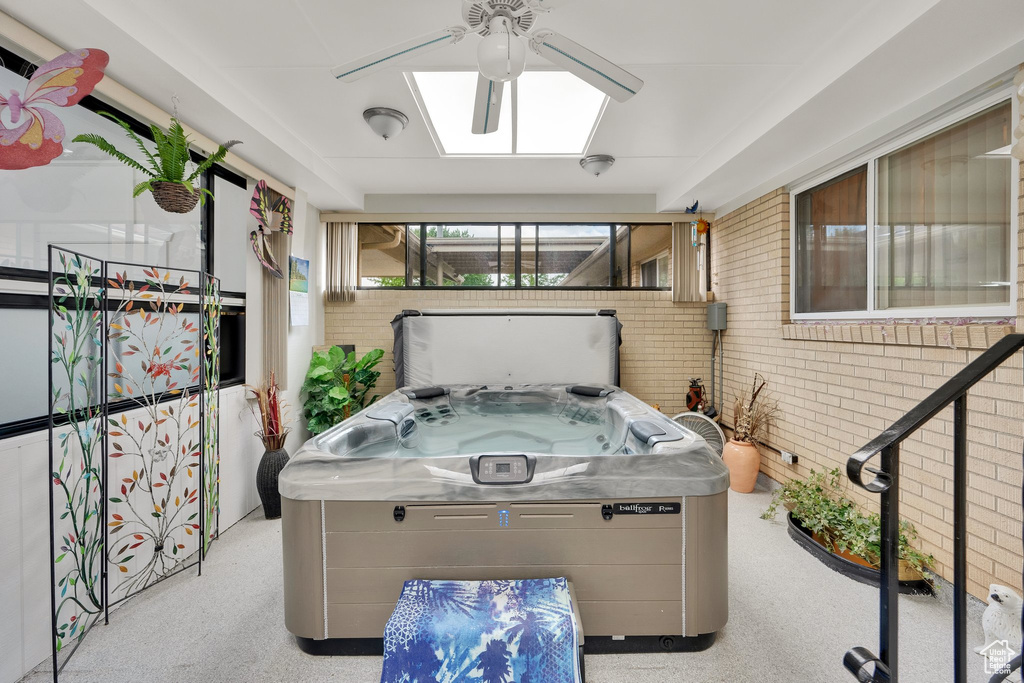 Sunroom with a hot tub and a skylight