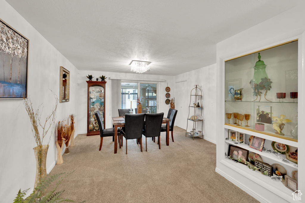 Carpeted dining space featuring a chandelier and baseboards