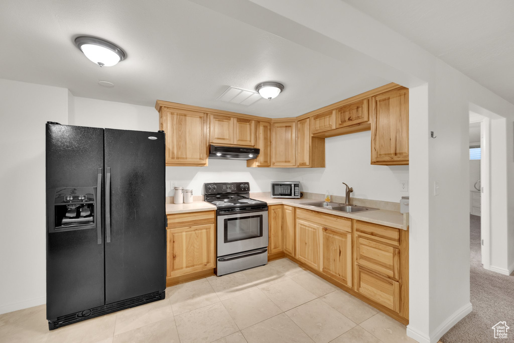 Kitchen with black fridge with ice dispenser, electric stove, a sink, under cabinet range hood, and light brown cabinetry