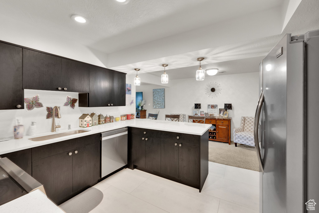 Kitchen with appliances with stainless steel finishes, a sink, a peninsula, light countertops, and recessed lighting