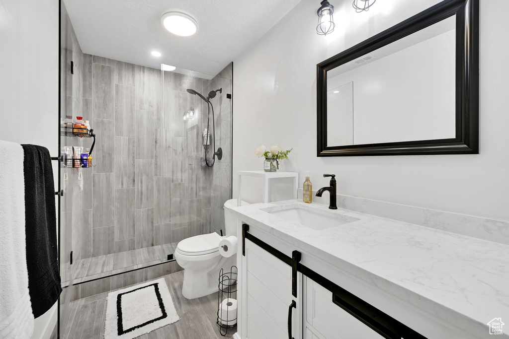 Full bath featuring toilet, vanity, and tiled shower