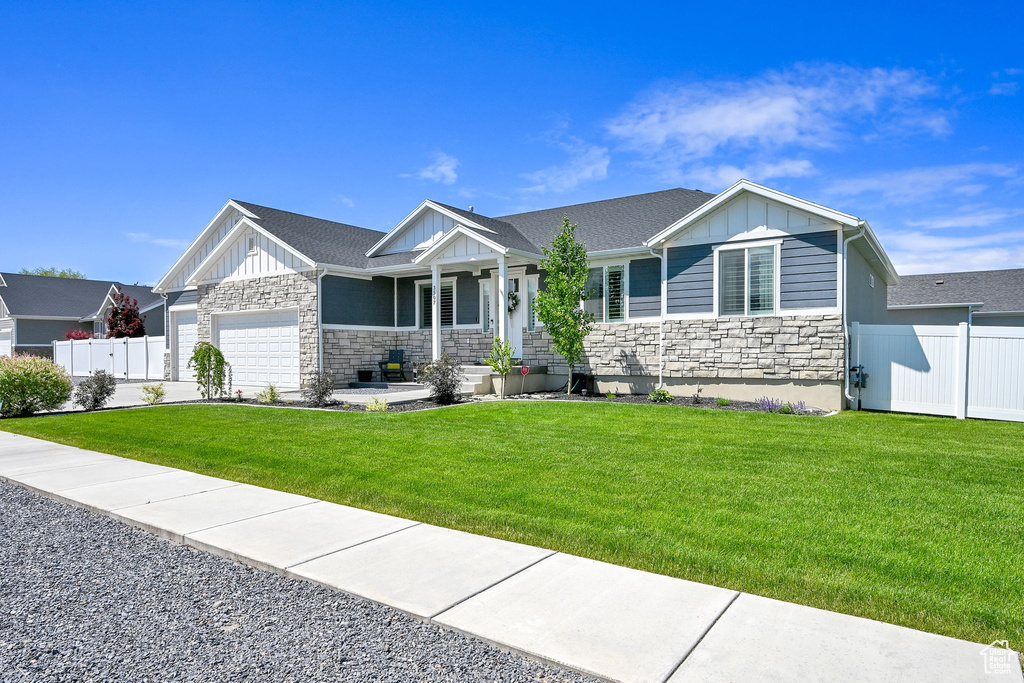 View of front of home with stone siding, board and batten siding, an attached garage, and a porch