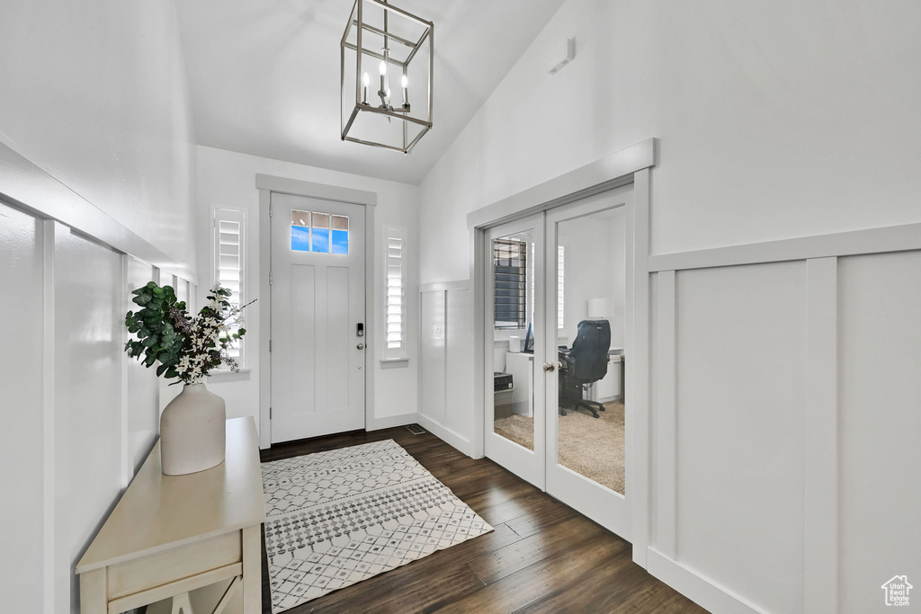 Entrance foyer with dark wood-type flooring, french doors, vaulted ceiling, and a chandelier