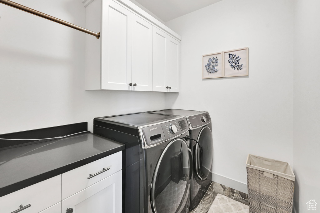 Washroom with cabinet space, washer and dryer, and baseboards
