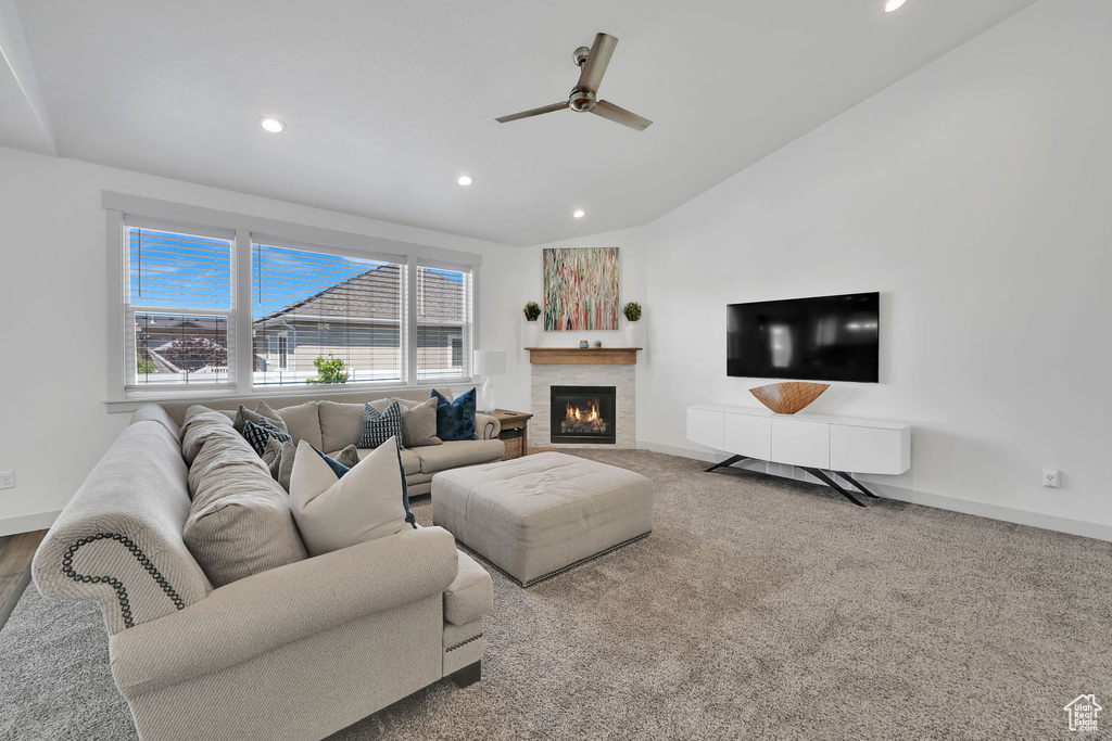 Living room featuring recessed lighting, lofted ceiling, a ceiling fan, a lit fireplace, and baseboards