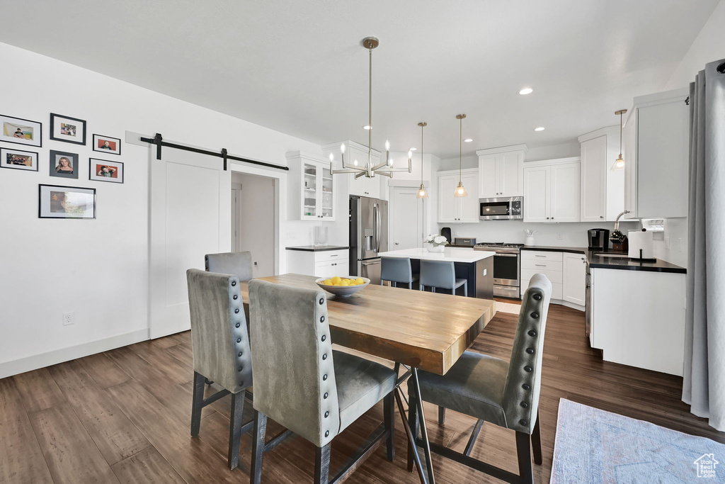 Dining room featuring a barn door, a chandelier, dark wood finished floors, baseboards, and recessed lighting