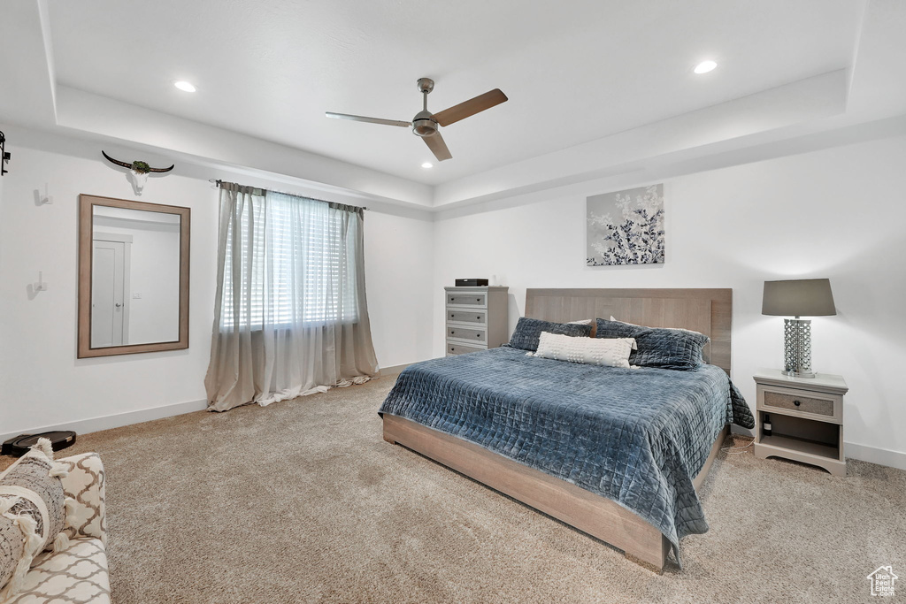 Carpeted bedroom featuring baseboards, a raised ceiling, recessed lighting, and ceiling fan