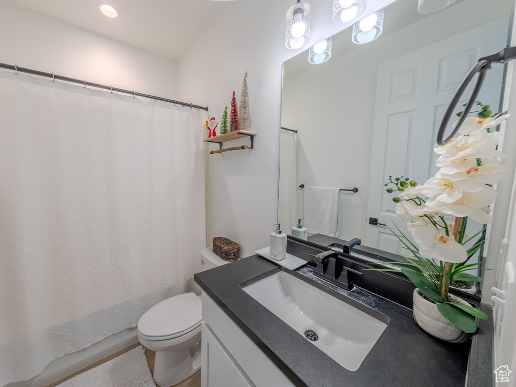 Bathroom with toilet, vanity, and recessed lighting