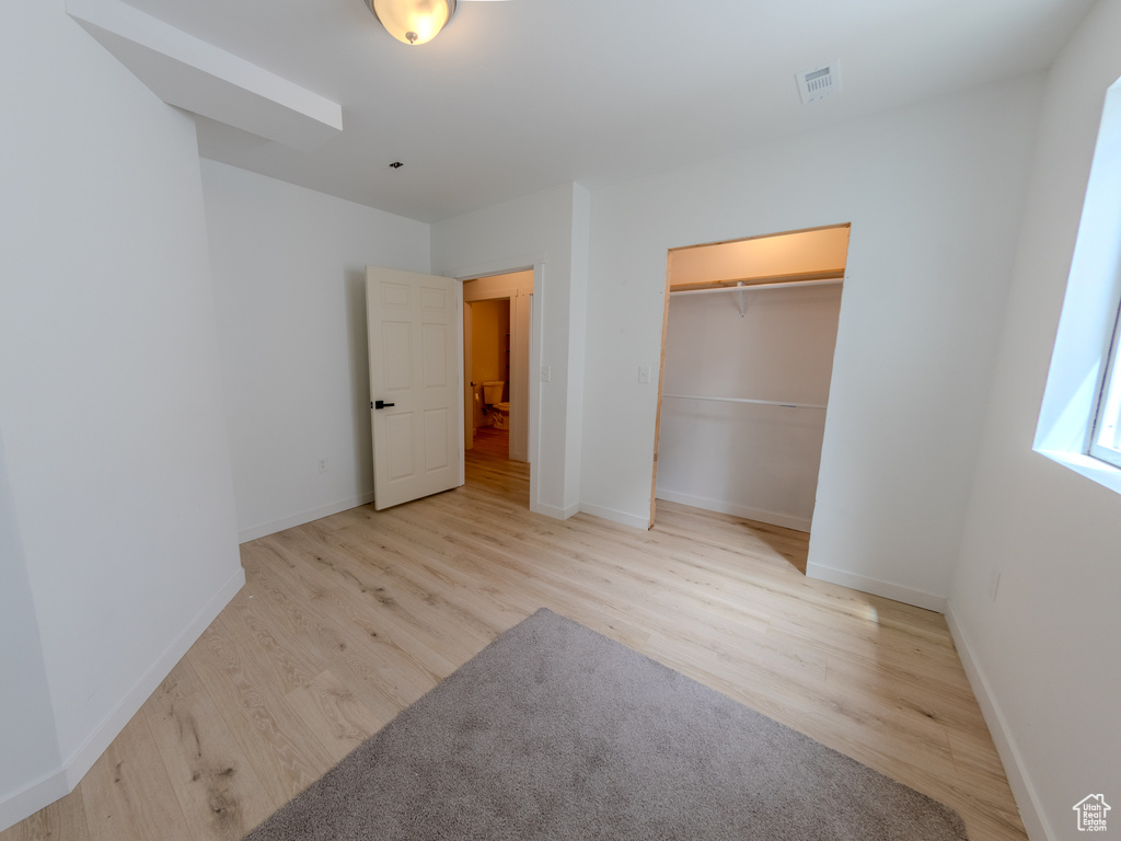 Unfurnished bedroom with wood finished floors, baseboards, and a closet