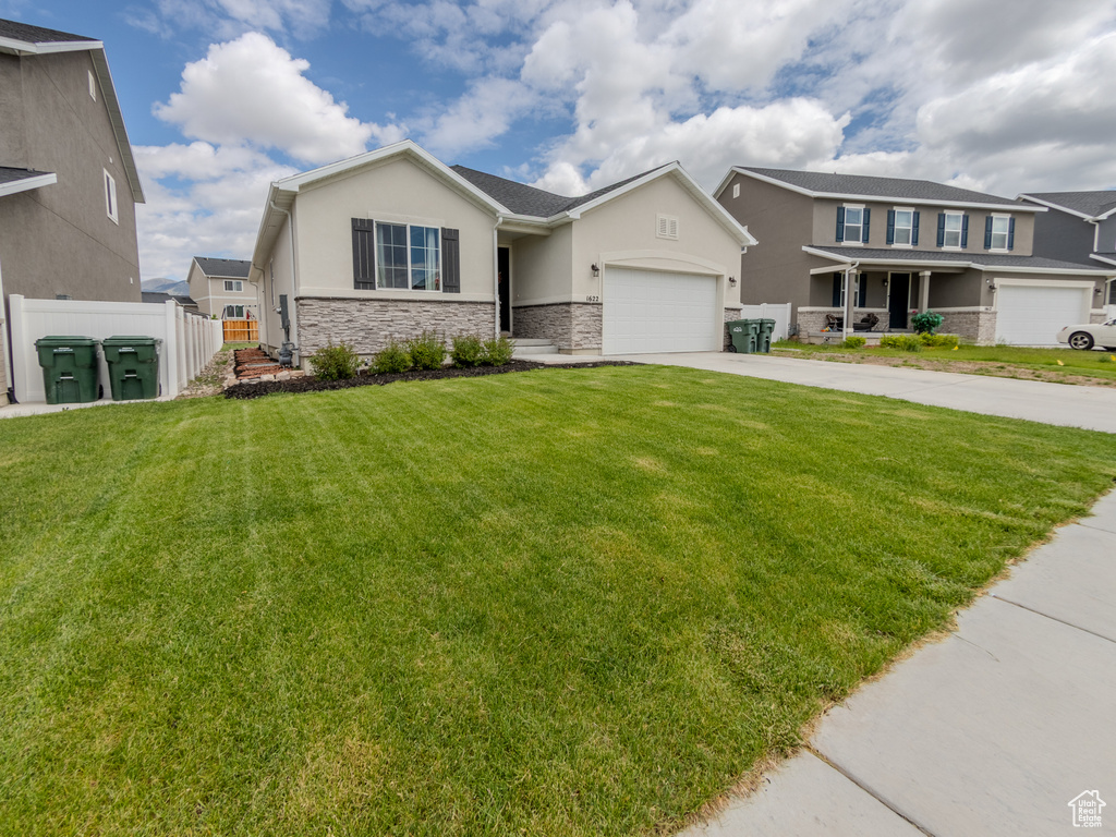 View of front of home with stucco siding, stone siding, concrete driveway, and a garage