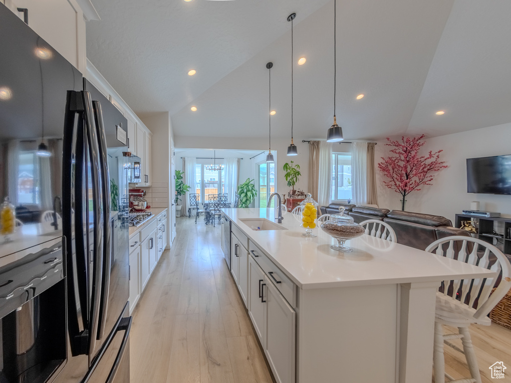 Kitchen with freestanding refrigerator, a sink, white cabinetry, light wood-style floors, and recessed lighting