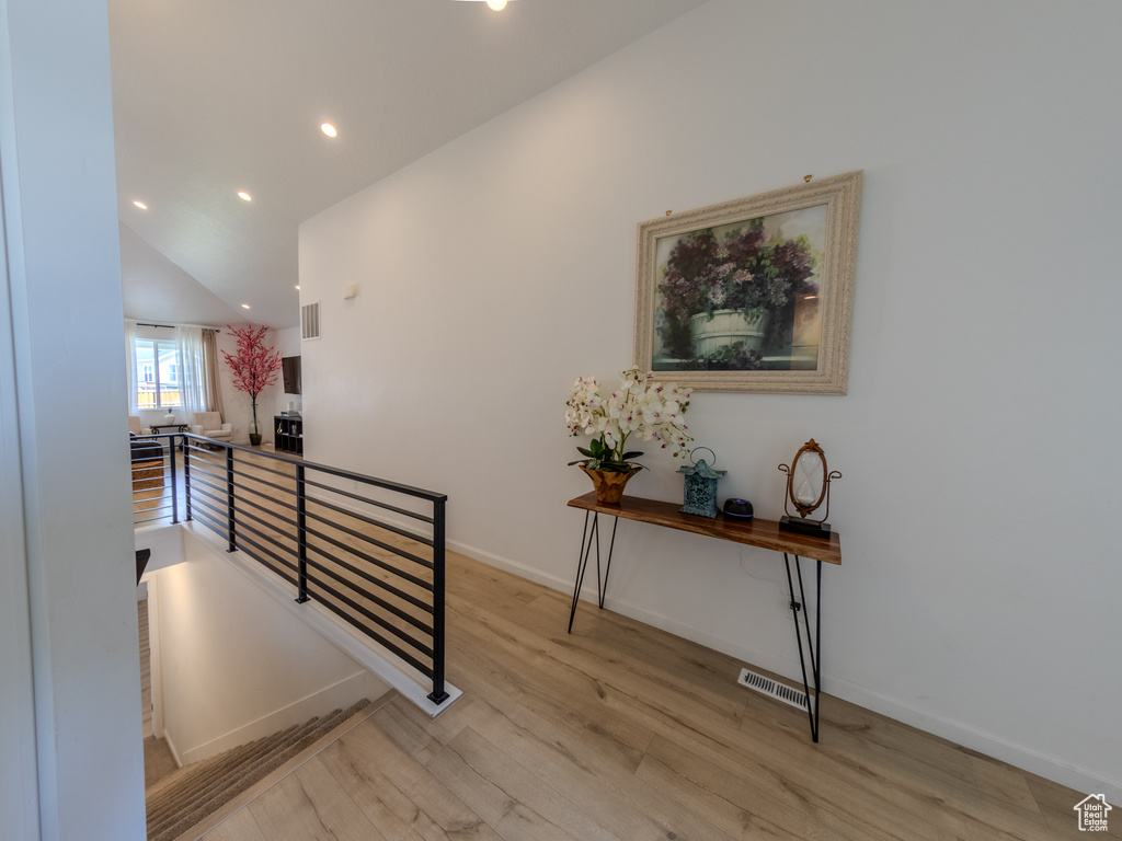 Hallway with an upstairs landing, light wood-style floors, recessed lighting, baseboards, and lofted ceiling
