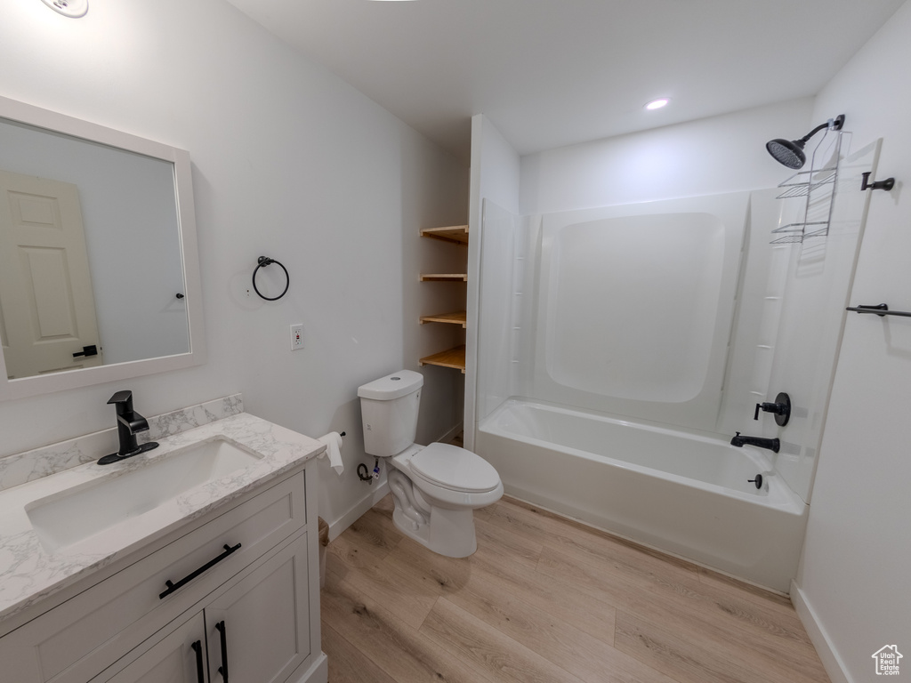 Full bathroom with wood finished floors, toilet, vanity, bathtub / shower combination, and baseboards