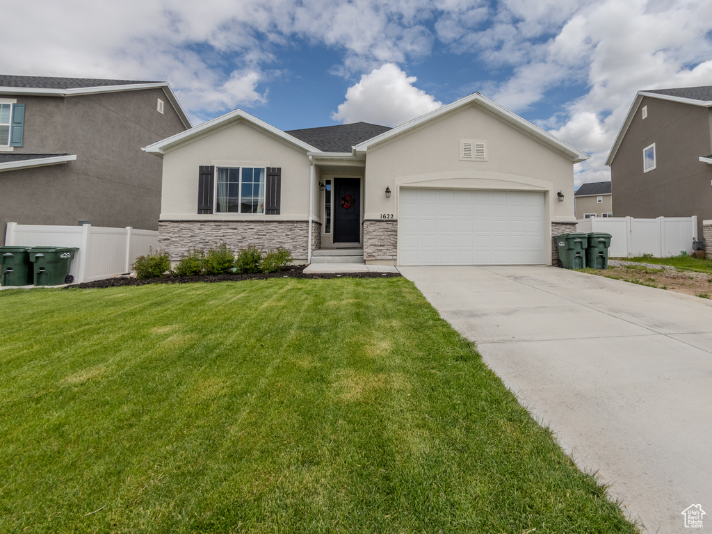 View of front of home with stucco siding, stone siding, an attached garage, and concrete driveway