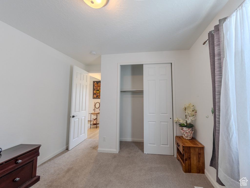 Bedroom with light carpet, a closet, and baseboards