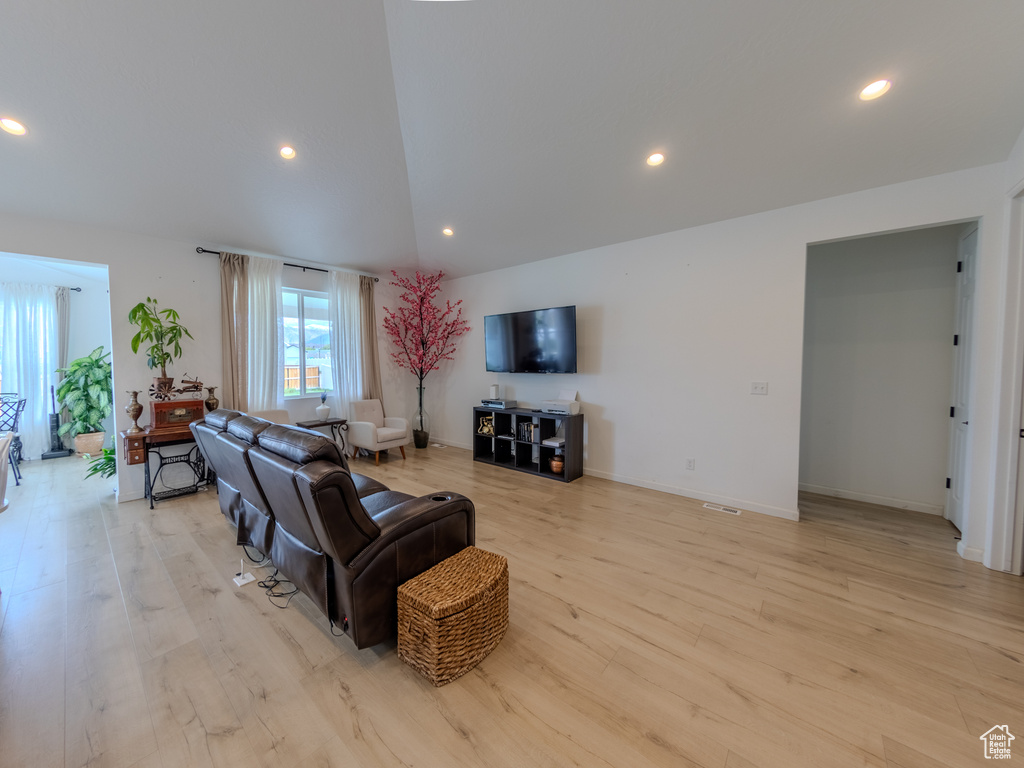Living area featuring recessed lighting, light wood finished floors, lofted ceiling, and baseboards